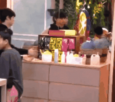 Woman Standing In Front Of Counter With Bottles And Boxes GIF