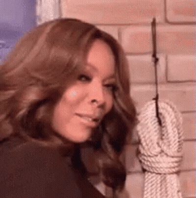 Woman Standing In Front Of Hanging Rope On Brick Wall GIF