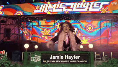 Woman Standing In Front Of Jamie Hayter Sign GIF