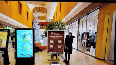 Woman Standing In Front Of Tchibo Sign GIF