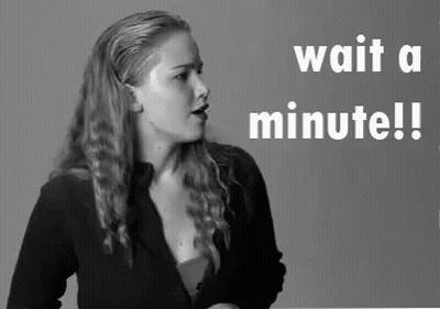 Woman Standing In Front Of Wait A Minute Sign GIF