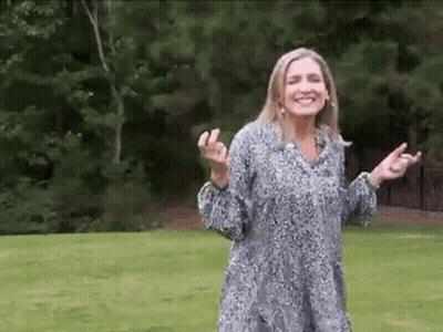 Woman Standing In Grassy Field With Arms Outstretched Smiling GIF