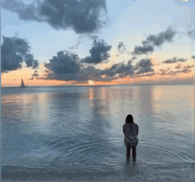 Woman Standing In Water At Sunset GIF