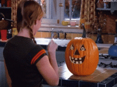 Woman Standing Next To Carved Pumpkin GIF