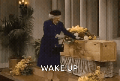 Woman Standing Next To Coffin Says Wake Up GIF