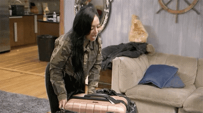 Woman Standing Next to Couch Holding Suitcase