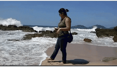 Woman Standing On Beach Looking At Phone GIF