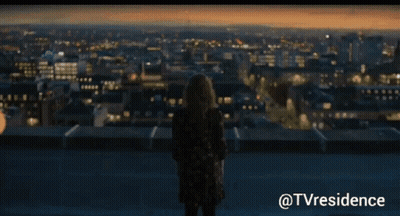 Woman Standing On Rooftop Over City GIF