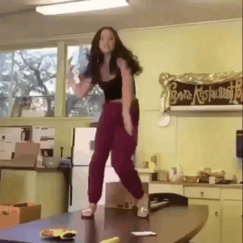 Woman Standing On Table In Front Of General Restaurant Sign GIF