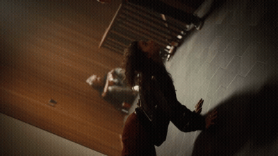 Woman Standing On Tiled Floor With Man Sitting Behind GIF