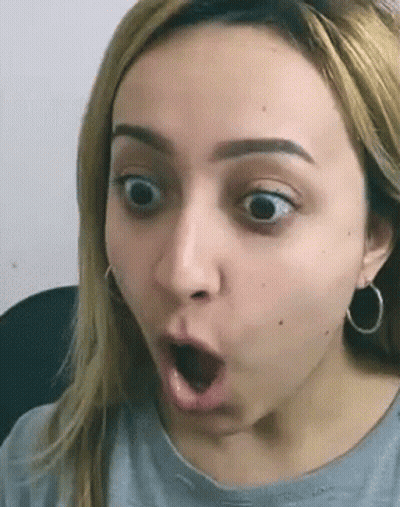 Woman Surprised Wearing Earrings And Gray Shirt GIF