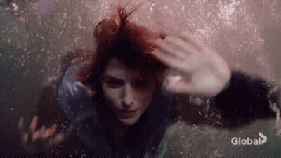 Woman Swimming Underwater Eyes Closed Bubbles From Hair GIF