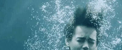 Woman Swimming Underwater Eyes Closed Bubbles From Hair GIF