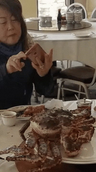 Woman Taking Picture Of Large Crab On Plate GIF