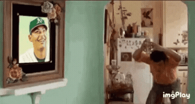 Woman Taking Picture Of Man In Baseball Cap In Front Of Picture Frame GIF