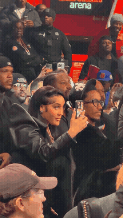 Woman Taking Picture Of Man In Front Of Arena GIF