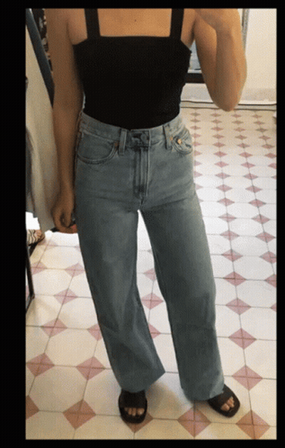 Woman Taking Selfie In Black Tank Top And Wide Leg Jeans GIF