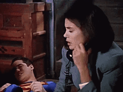 Woman Talking On Phone While Superman Lies On Floor GIF