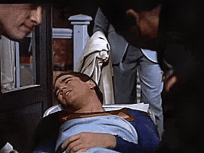 Woman Talking On Phone While Superman Lies On Floor GIF