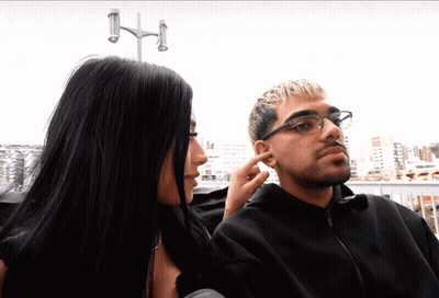 Woman Touching Man's Ear While He Looks At Her GIF