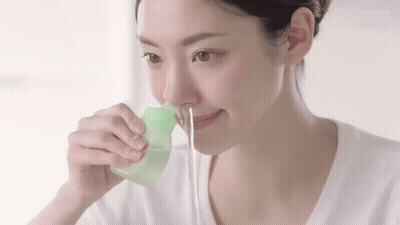 Woman Using Green Container To Clean Nose GIF