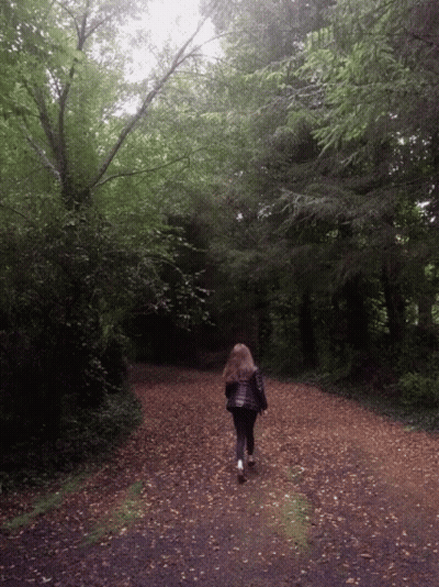 Woman Walking Down Dirt Road In Woods GIF