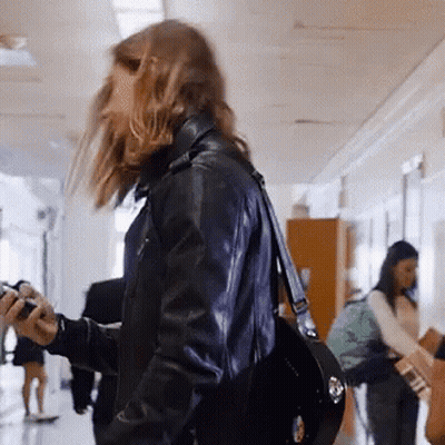 Woman Walking Down Hallway Holding Camera GIF