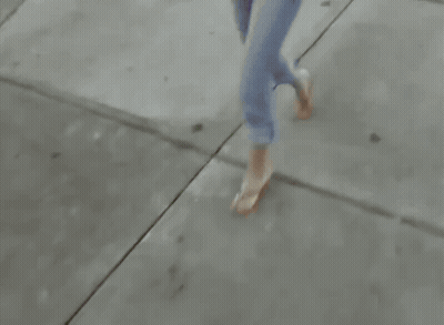 Woman Walking Down Sidewalk Carrying Books and Purse