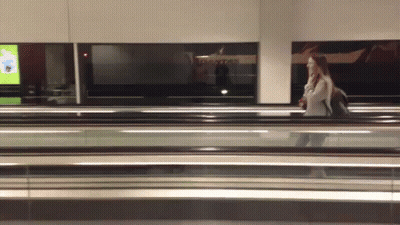 Woman Walking On Escalator Past Qantas Sign GIF