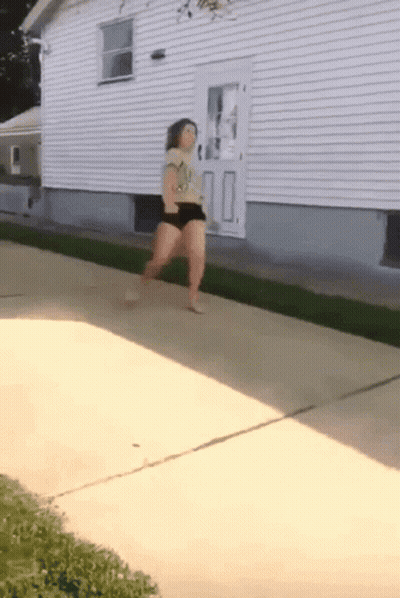Woman Walking On Sidewalk Near House GIF