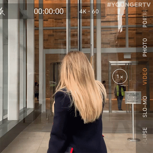 Woman Walking Past Building With No Cell Phones Sign GIF