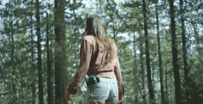 Woman Walking Through Woods With Gun In Pocket GIF