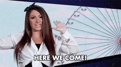 Woman Waving In Front Of Ferris Wheel Saying Here We Come GIF