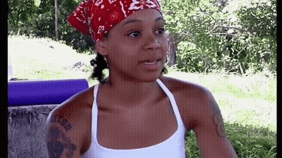 Woman Wearing Bandana And White Tank Top Standing In Grass GIF