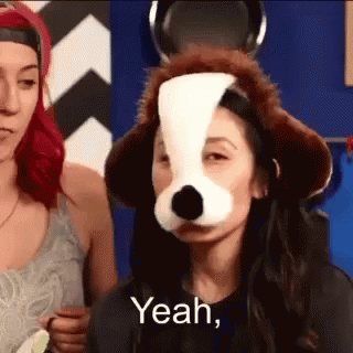 Woman Wearing Dog Mask Standing Next To Woman Wearing Hat GIF