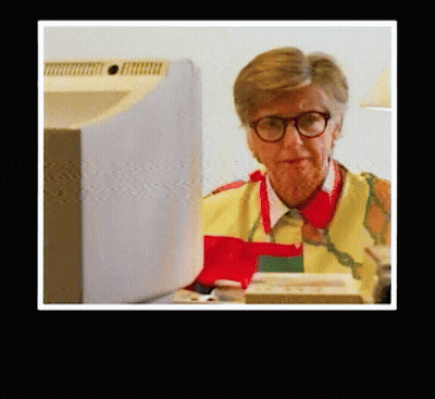 Woman Wearing Glasses And Apron At Computer GIF