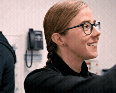 Woman Wearing Glasses And Black Shirt Smiling In Front Of Telephone GIF