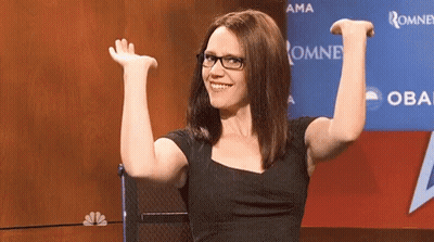 Woman Wearing Glasses Sitting In Front Of Oma Sign GIF