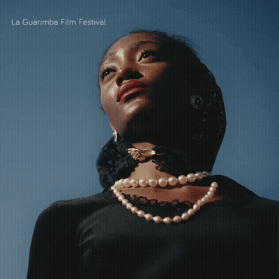 Woman Wearing Pearl Necklace Looking At La Guarimba Poster GIF