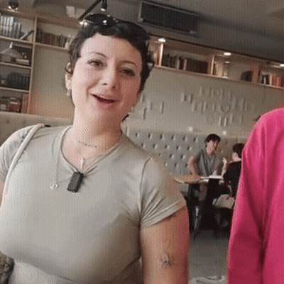 Woman With Arm Tattoo Smiling In Front Of How Wonderful Wall GIF