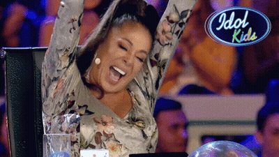 Woman With Arms In Air Sitting In Front Of Idol Kids Logo GIF