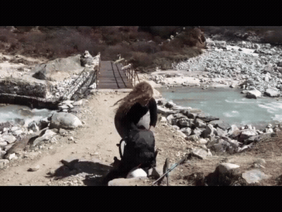 Woman With Backpack Walking Across Bridge GIF