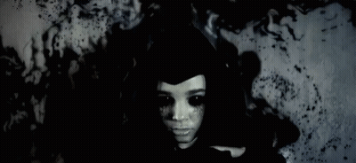 Woman With Black Eyes And Black Hat In Dark Room GIF