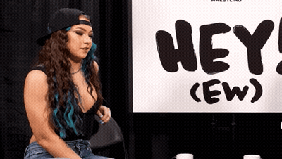 Woman With Blue Hair Sitting In Front Of Hey (Ew) Sign GIF
