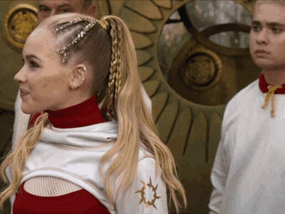 Woman With Braided Ponytail In White Top With Gold Star GIF