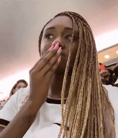 Woman With Braids And Pink Nails Covering Mouth GIF
