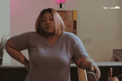 Woman With Brown Hair Sitting By Christmas Tree GIF