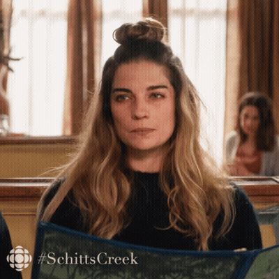 Woman With Bun Holding Schitt's Creek Book GIF