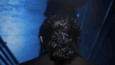 Woman With Bun Standing In Dark Room GIF