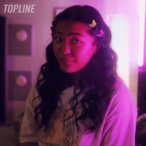 Woman With Butterfly In Hair Standing In Front Of Topline Sign GIF